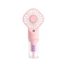 A pink handheld mini fan with a clear base and a pink central button. The base has NSK and COOL MIST SPRAY MINI FAN printed in blue and red. The fan has a circular grill with a flower-like design.