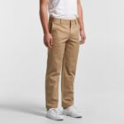 Person wearing khaki pants, white t-shirt, and white sneakers, standing against a plain background.