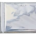 A silver, crinkled, rectangular foil wrapper, partially opened on one side, likely used for packaging a consumable item such as chocolate or snacks, set against a plain white background.