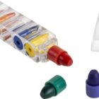 A transparent rectangular crayon holder containing five multicolored crayon tips arranged horizontally. Nearby are red, green, and blue crayon tips lying separately. A clear triangular stand is also visible.