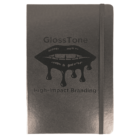 A black notebook with the brand name GlossTone and tagline High-Impact Branding on the cover. The design features stylized lips with dripping gloss. The notebook has rounded corners and an elastic band for closure.