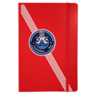Red notebook with an elastic band on the right. It features diagonal white stripes on the left and a Club Puebla crest with a burning torch and water waves in the center.