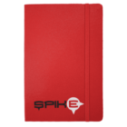 A red notebook with a black and white logo that reads SPIKE on the front cover. An elastic band wraps vertically around the right edge, securing the notebook.