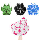 Four paw-shaped signs with logos: green, black, blue, and a large pink one held up by a hand. Each sign displays a different logo design within the paw shape. The pink sign is in the foreground.