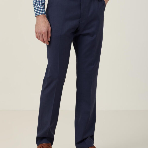 A person in a blue checkered shirt and navy trousers stands with hands in pockets. They are wearing brown leather sneakers and a brown belt. The image shows the outfit without revealing the persons face.