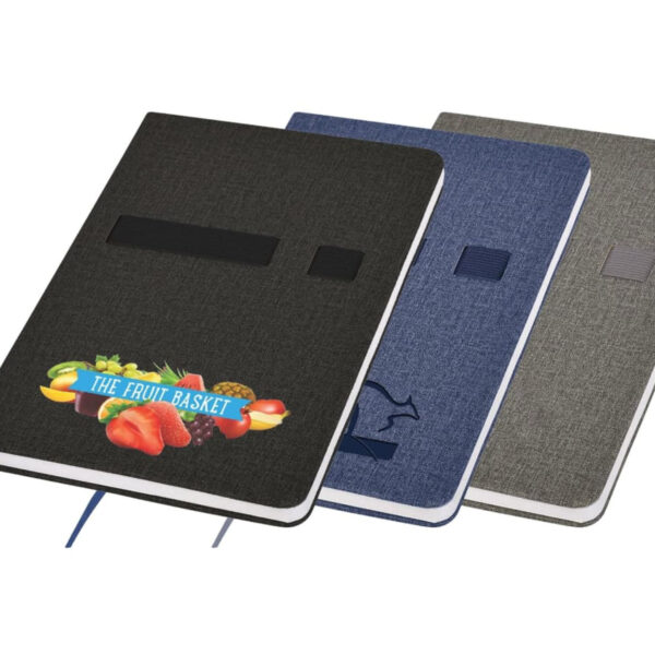 The Emz A5 Notebook collection features three hardcover options with fabric covers in black, blue, and gray. The black version has a fruit logo and The Fruit Basket text. All notebooks include a ribbon bookmark and an elastic band closure for convenience.