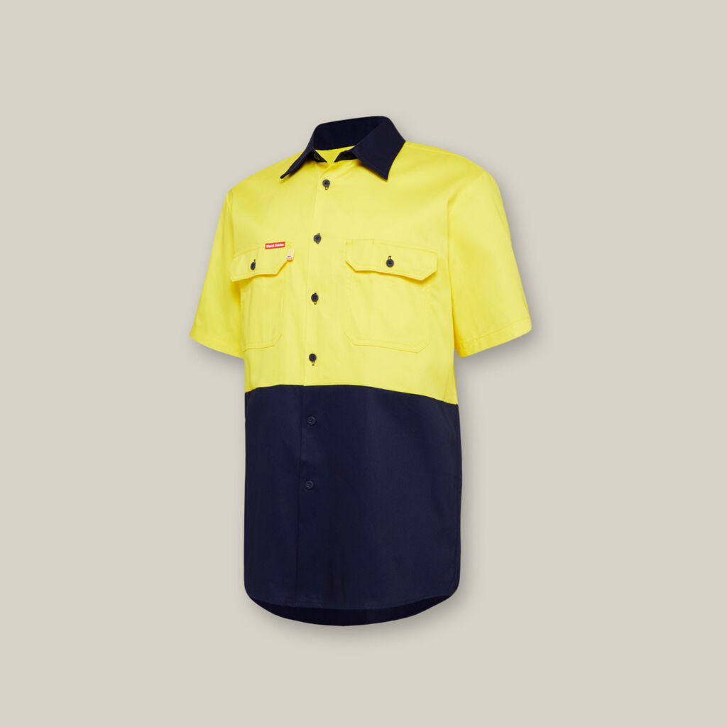 This short-sleeved shirt, with a yellow upper and dark blue lower half, includes two buttoned chest pockets and a front button closure. Ideal for outings with your Emz A5 Notebook, it stands out beautifully against a neutral background.