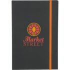 A black notebook with the logo Market Street in orange and red on the front. An orange elastic band is wrapped vertically around the right side.