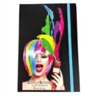 A notebook cover featuring a woman with vibrant rainbow-colored hair, holding a paintbrush. Bright paint splashes emerge from the brush. Text reads ColourSplash High-Impact Branding. A turquoise elastic band is on the right.