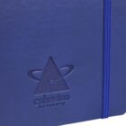 Close-up of a blue notebook cover with an embossed design featuring a triangle surrounded by an orbital shape. Below is the text cohesion training. An elastic band runs vertically along the right edge.