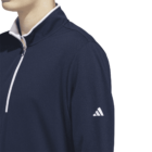 Person wearing a navy quarter-zip pullover with Adidas logo on the sleeve.