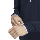 Person adjusting the cuff of a navy blue long-sleeve top with white trim.