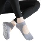 Person wearing black leggings and gray no-show socks with white non-slip grips sitting with legs crossed.