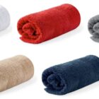 Five rolled-up towels in white, red, gray, beige, and navy blue colors on a white background.