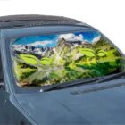 Car with a windshield sunshade showing a mountain landscape and green leaf graphics.