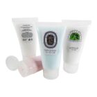 Four tubes of lotion with different labels and colors, two upright and two lying down.