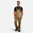 Man in tan overalls and black t-shirt styled with Explorer Shield, against white background.