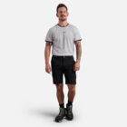 Man in an Explorer Shield gray t-shirt, black shorts, and boots against a white background.