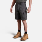 Man wearing gray cargo shorts, brown work boots, dark shirt, and the Explorer Shield.