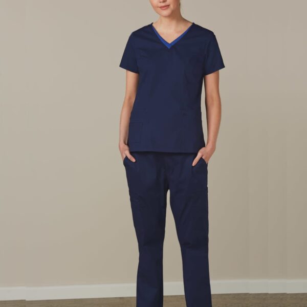 Person standing in blue medical scrubs and white shoes against a plain background.