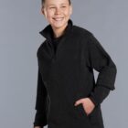 Smiling boy in a dark fleece pullover with one hand in his pocket against a gray background.