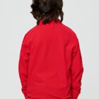 Person with long brown hair wearing a red sweater, photographed from behind against a plain background.