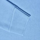 Close-up of a light blue sweater sleeve cuff on a matching blue background.