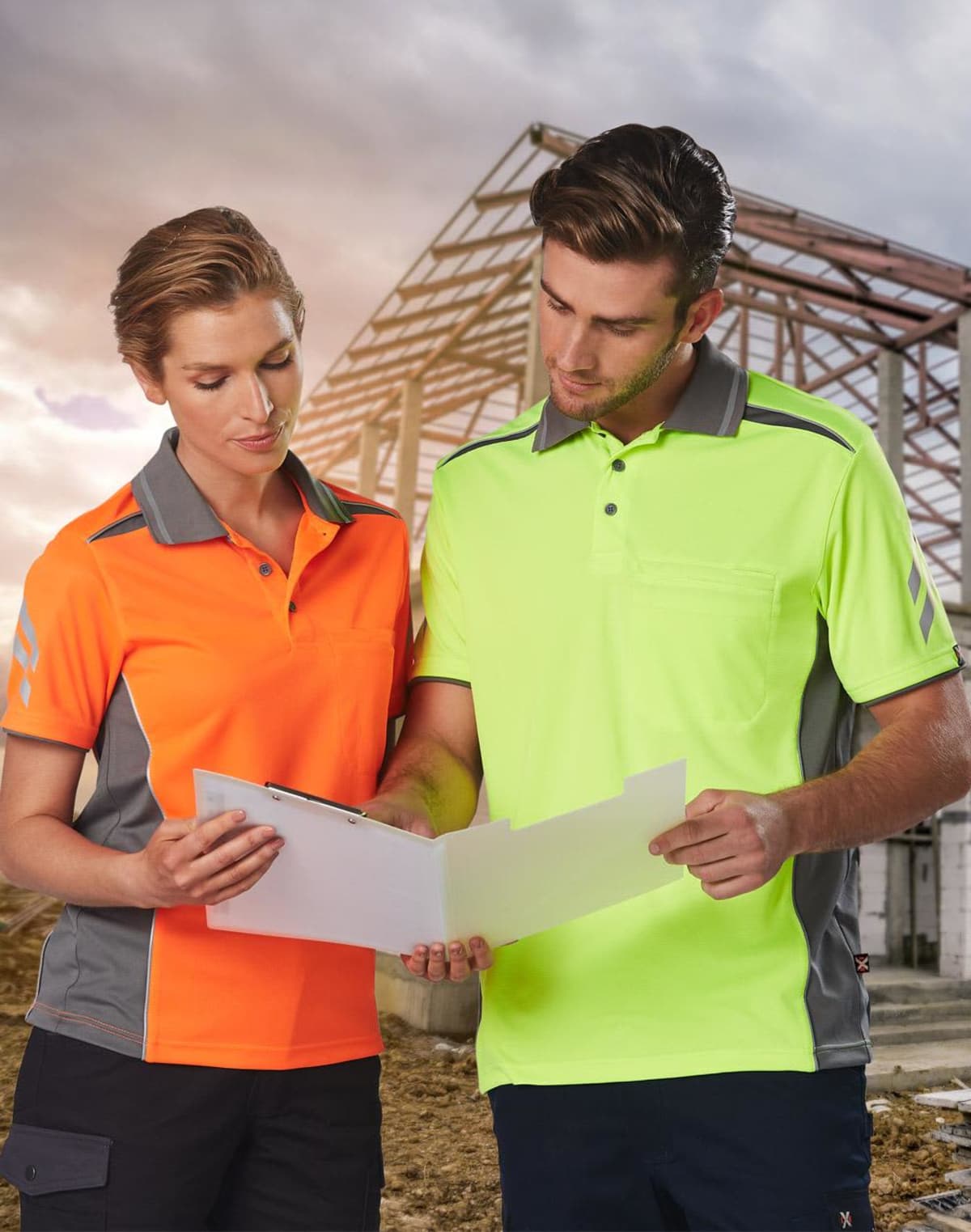 Two people in high-visibility shirts reviewing documents at a construction site.