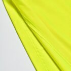 Close-up of bright yellow fabric with visible stitching and textured surface.