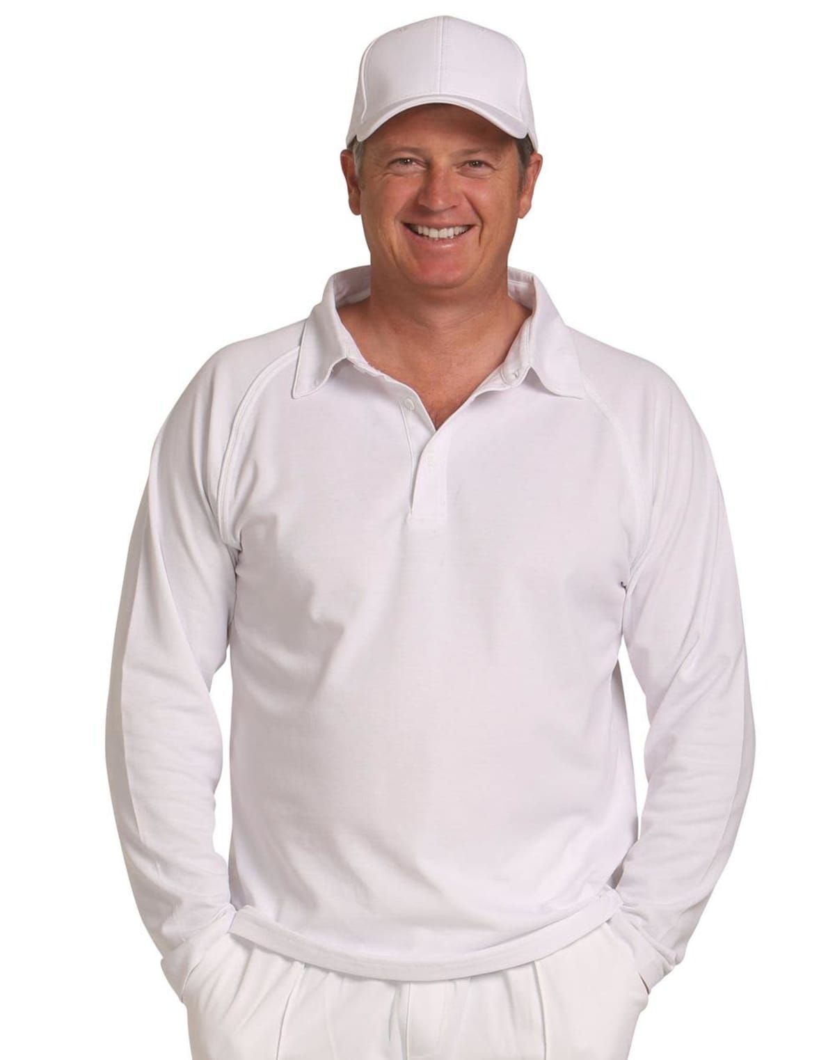 Smiling man in white sports attire and cap with hands in his pockets.