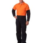 Man wearing an orange and navy work uniform, standing and smiling against a white background.