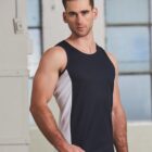 Man in a sleeveless black and white athletic shirt standing indoors by large windows.