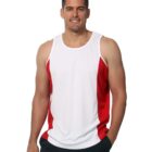 Man in a white and red tank top smiling, standing with one hand in his pocket.