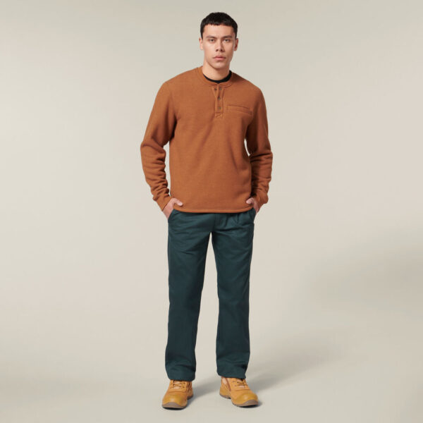 Man in brown sweater, green pants, tan shoes, holding an Explorer Shield.