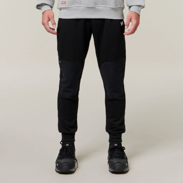 Man wearing black joggers, black sneakers, gray sweatshirt, and an Explorer Shield.