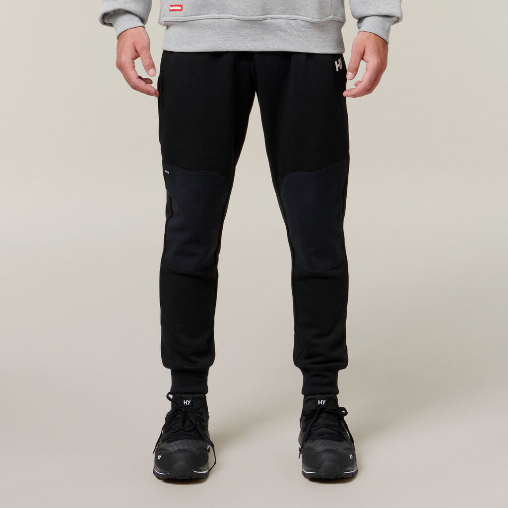 Man wearing black joggers, black sneakers, gray sweatshirt, and an Explorer Shield.
