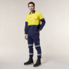 A person in a high-visibility yellow and navy blue work uniform, featuring reflective strips on the long-sleeved shirt and pants along with sturdy black work boots, stands against a neutral background resembling the Emz A5 Notebooks clean lines.