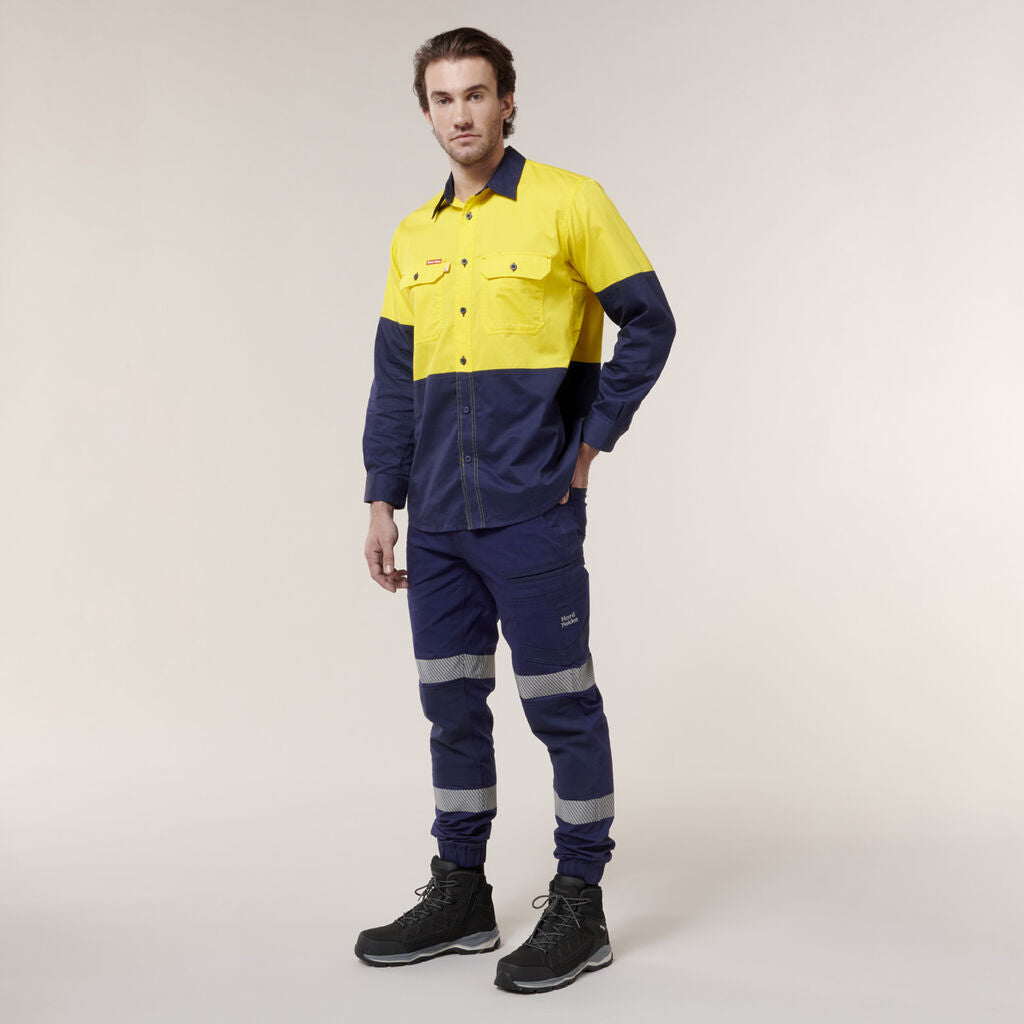A person in a high-visibility yellow and navy blue work uniform, featuring reflective strips on the long-sleeved shirt and pants along with sturdy black work boots, stands against a neutral background resembling the Emz A5 Notebooks clean lines.