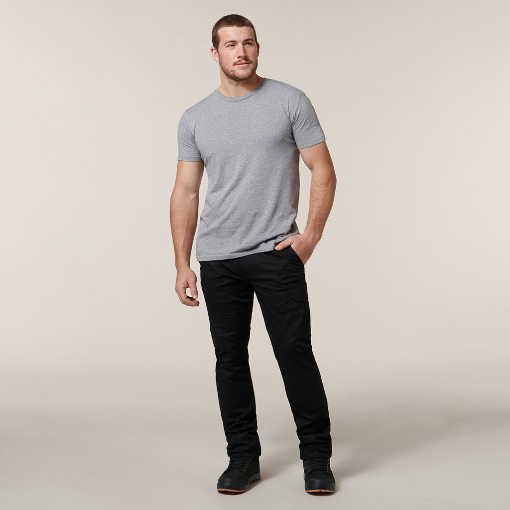 A man in gray and black attire stands against a plain background, casually jotting notes in his Emz A5 Notebook.