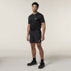 A person in a black t-shirt and shorts against a neutral background features Emz branding, completed with black socks and shoes for a sleek look.