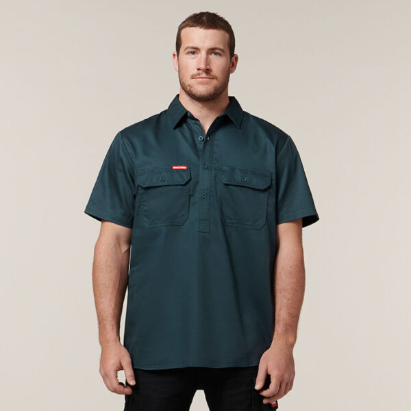 Man in a dark green Explorer Shield short-sleeve button-up shirt with two chest pockets.