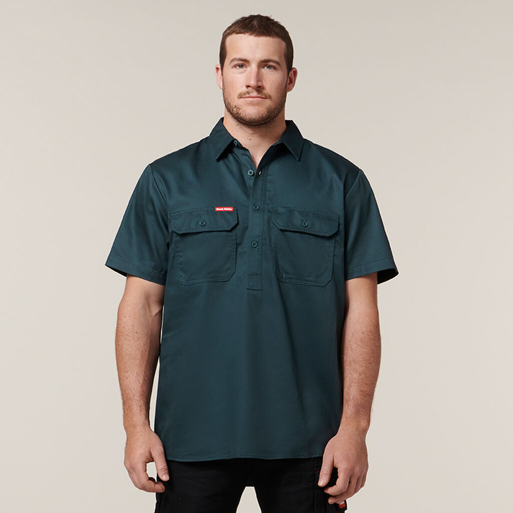Man in a dark green Explorer Shield short-sleeve button-up shirt with two chest pockets.