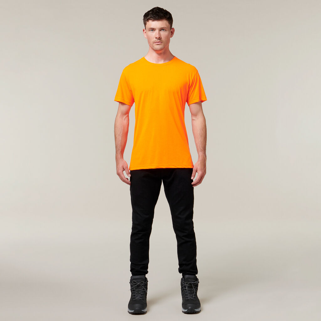 On a plain background, someone stands facing forward with arms relaxed by their sides, wearing an orange T-shirt, black pants, and black shoes—reminiscent of Emzs latest sketches in her Emz A5 Notebook.