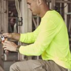 Man in a neon yellow shirt works with pliers on wires at a construction site.