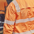 A person in an orange high-visibility safety jacket seen from behind.