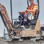 Construction worker operating a small excavator on a gravel site.