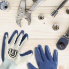 Workbench with tools and gloves on a light wood surface.