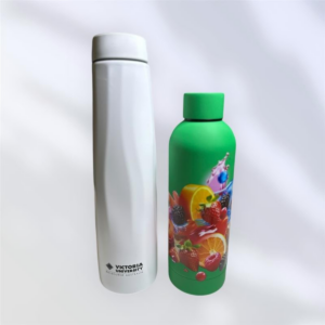 A tall, white promotional bottle with Victoria University text stands next to a shorter, green bottle adorned with colorful fruit graphics. Both bottles sit against a plain, light background.