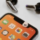 Smartphone with colorful apps, earphones, and a round privacy cover on the front camera.