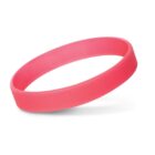 A pink rubber wristband on a white background, casting a soft shadow.